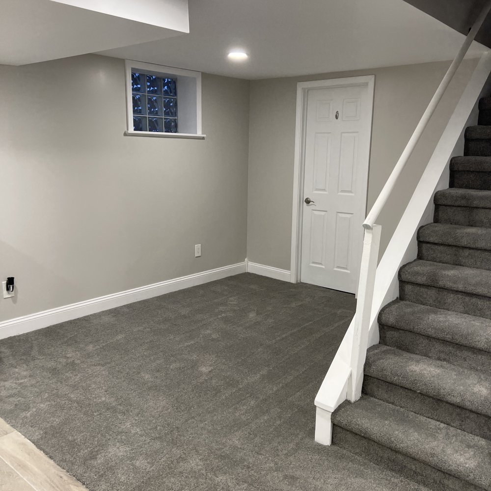 Eaton Home Improvements - a basement with carpet and stairs - General Contractors Near Me Eaton Home Improvements - a basement with carpet and stairs - General Contractors Near Me