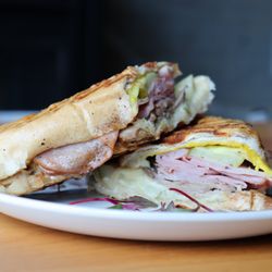 Cubano

Mojo pork, smoked ham, Swiss cheese, dill pickles, and yellow mustard pressed on buttery Cuban bread.