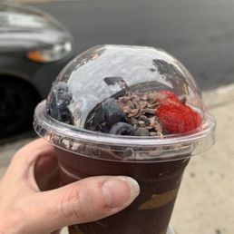 Beautiful 12 oz açaí bowl to go, with almond butter, strawberries, blueberries, and cacao nibs. Yum!