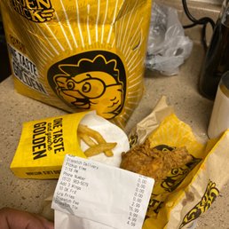 a person holding a receipt and a bag of chicken nuggies