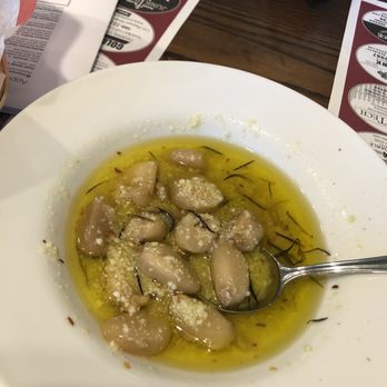 Briggs Corner Pizzeria - Garlic dipping sauce for the bread - A white bowl contains gnocchi coated in olive oil, garnished with grated cheese and herbs, on a wooden table with menus nearby. - Pizza Near Me - Attleboro, Massachusetts