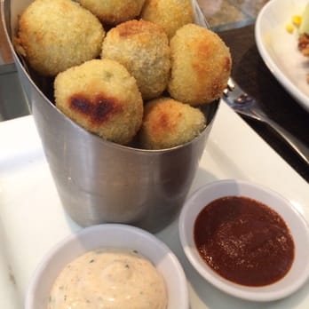 Seasons 52 - Tamale tots with chili sour cream and mole sauce. - New American Near Me - Plano, Texas