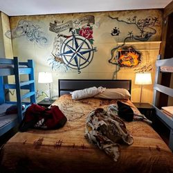 Pirate Haus Inn - King-sized bed with pirate-themed mural in background.