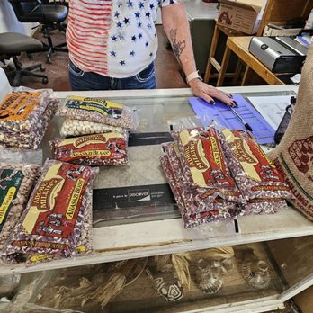 Adobe Milling - a woman standing in front of a table with bags of cereal - Specialty Food Near Me - Dove Creek, Colorado Adobe Milling - a woman standing in front of a table with bags of cereal - Specialty Food Near Me - Dove Creek, Colorado
