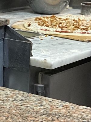Photo of John & Joe's Pizzeria - Bronx, NY, US. A cockroach on the corner of the counter where the pizza is being made.