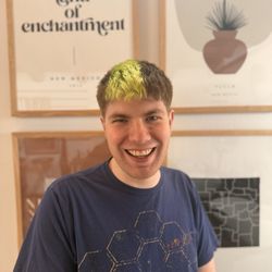Hairpins & Scissors - Front view of a haircut on a young male. Short hair with an asymmetric dyed hair strip with bright green.
