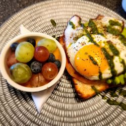 Avocado open face sandwich with a side fruit bowl.