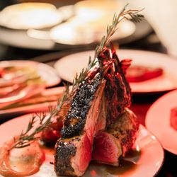Revel Steak - Perfectly seared Rack of Lamb with a beautifully tender center and bold, savory flavor, artfully presented at Revel Steak.