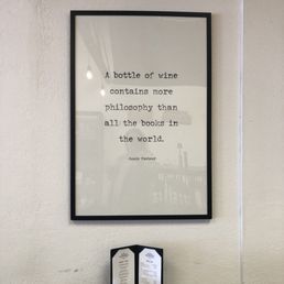 A sign with the quote "A bottle of wine contains more philosophy than all the books in the world." by Louis Pasteur