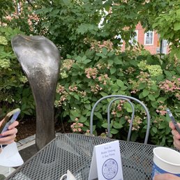 Corner outdoor table with a bronze sculpture of what looks like the back of a cobra's head Corner outdoor table with a bronze sculpture of what looks like the back of a cobra's head