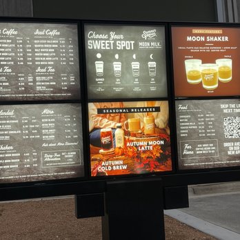 Summer Moon Coffee - Drive through menu - A digital menu board at Summer Moon Coffee features sections for hot and iced coffee, tea, seasonal releases, and food items, with prices and descriptions. - Coffee & Tea Near Me - Bee Cave, Texas