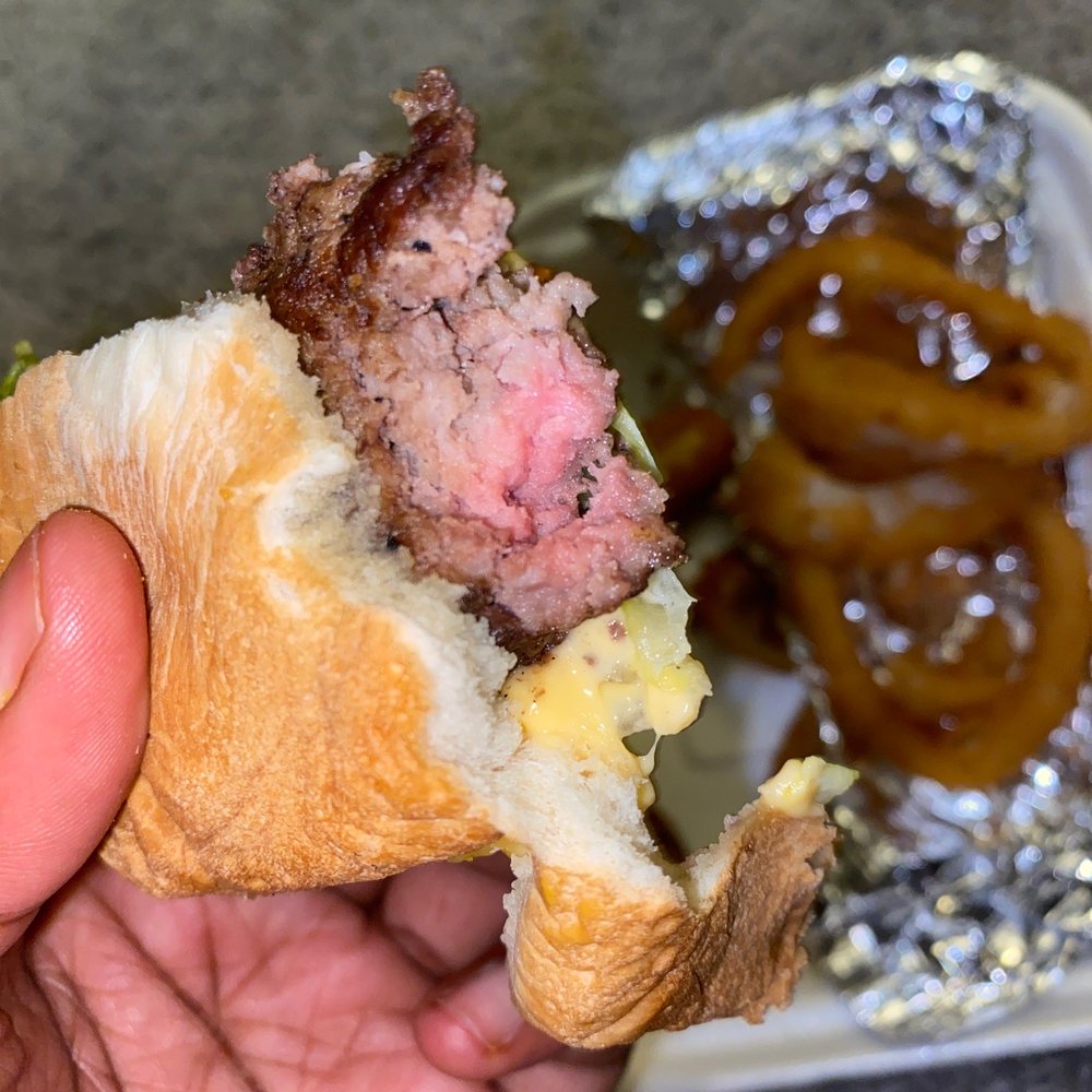 Cook Out - a hand holding a half eaten sandwich - Burgers Near Me - Tucker, Georgia Cook Out - a hand holding a half eaten sandwich - Burgers Near Me - Tucker, Georgia