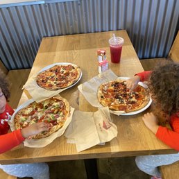 two children eating pizza at a table two children eating pizza at a table