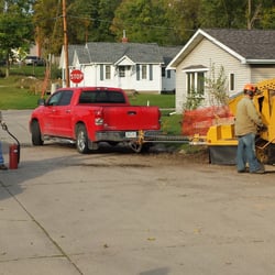 Cy's Tree Service - Cy grinding a tree stump with an exposed gas line uprooted by a tornado.