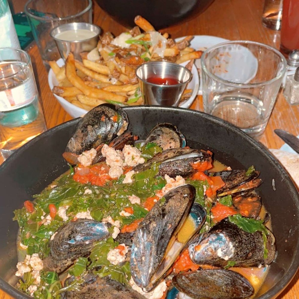 District Kitchen & Bar - PEl mussels crumbled sausage, kale, tomato ragu and grilled baguette. W a side order of the truffle fries. - New American Near Me - Pittsfield, Massachusetts District Kitchen & Bar - PEl mussels crumbled sausage, kale, tomato ragu and grilled baguette. W a side order of the truffle fries. - New American Near Me - Pittsfield, Massachusetts
