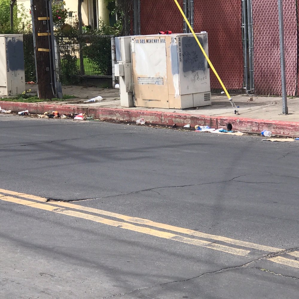 Garbage dumped in the gutter and sidewalk by 7/Eleven customers on the side of their store.