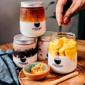 KOKONUT - Cloud Kitchen - a person putting a spoon into a jar of yogurt - Desserts Near Me - Anaheim, California KOKONUT - Cloud Kitchen - a person putting a spoon into a jar of yogurt - Desserts Near Me - Anaheim, California