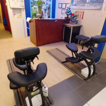 Relax Spa - Two massage chairs face a reception desk decorated with holiday ornaments, including a small Christmas tree and red hanging decorations. - Massage Near Me - Schaumburg, Illinois