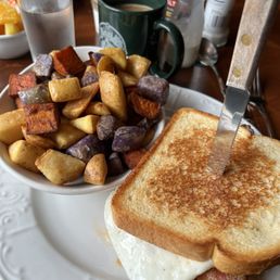Breakfast sandwich with bacon and a side of potatoes