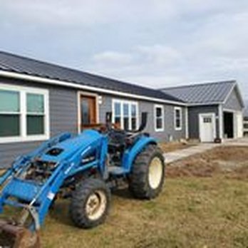 Gurden Construction - a blue tractor parked in front of a house - General Contractors Near Me - Cadillac, Michigan Gurden Construction - a blue tractor parked in front of a house - General Contractors Near Me - Cadillac, Michigan