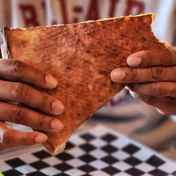 New York Pizza and Pints - a person holding a piece of pizza - Pizza Near Me - Frisco, Texas New York Pizza and Pints - a person holding a piece of pizza - Pizza Near Me - Frisco, Texas