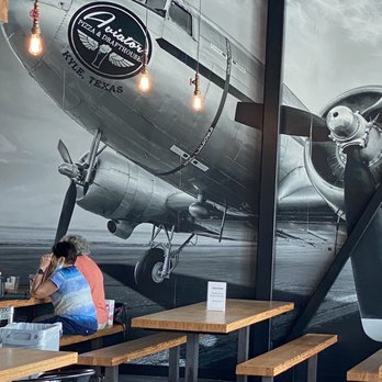Aviator Pizza & Drafthouse - a man sitting at a table - Pizza Near Me - Kyle, Texas Aviator Pizza & Drafthouse - a man sitting at a table - Pizza Near Me - Kyle, Texas