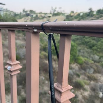 Frontier Internet - Optical cable hanging in the air attached by a clip to fence - Telecommunications Near Me Frontier Internet - Optical cable hanging in the air attached by a clip to fence - Telecommunications Near Me