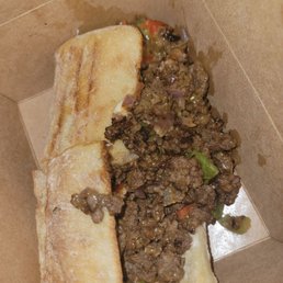 Chopped Cheeseeeeeee - A sandwich with cooked ground beef, chopped vegetables, and melted cheese inside a toasted bread roll, served in a brown paper container.