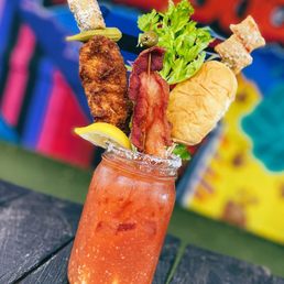 a bloody drink with bacon, lettuce, and lemon wedges