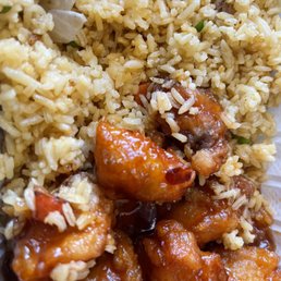 General Tso's Chicken and pork fried rice - A detailed close-up of fried rice mixed with vegetables and topped with saucy, battered chicken pieces from a Chinese fast food restaurant.