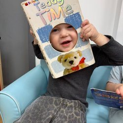 Little Builders International Academy - Toddler building early literacy skills while enjoying a book.