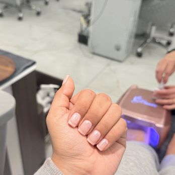 Element Nail Bar - Builder gel! - A person's hand with neatly manicured nails is visible, with a nail salon environment in the background, including chairs and salon equipment. - Nail Salons Near Me - Phoenix, Arizona