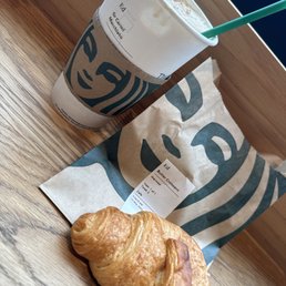 A hot caramel macchiato with a butter croissant A hot caramel macchiato with a butter croissant