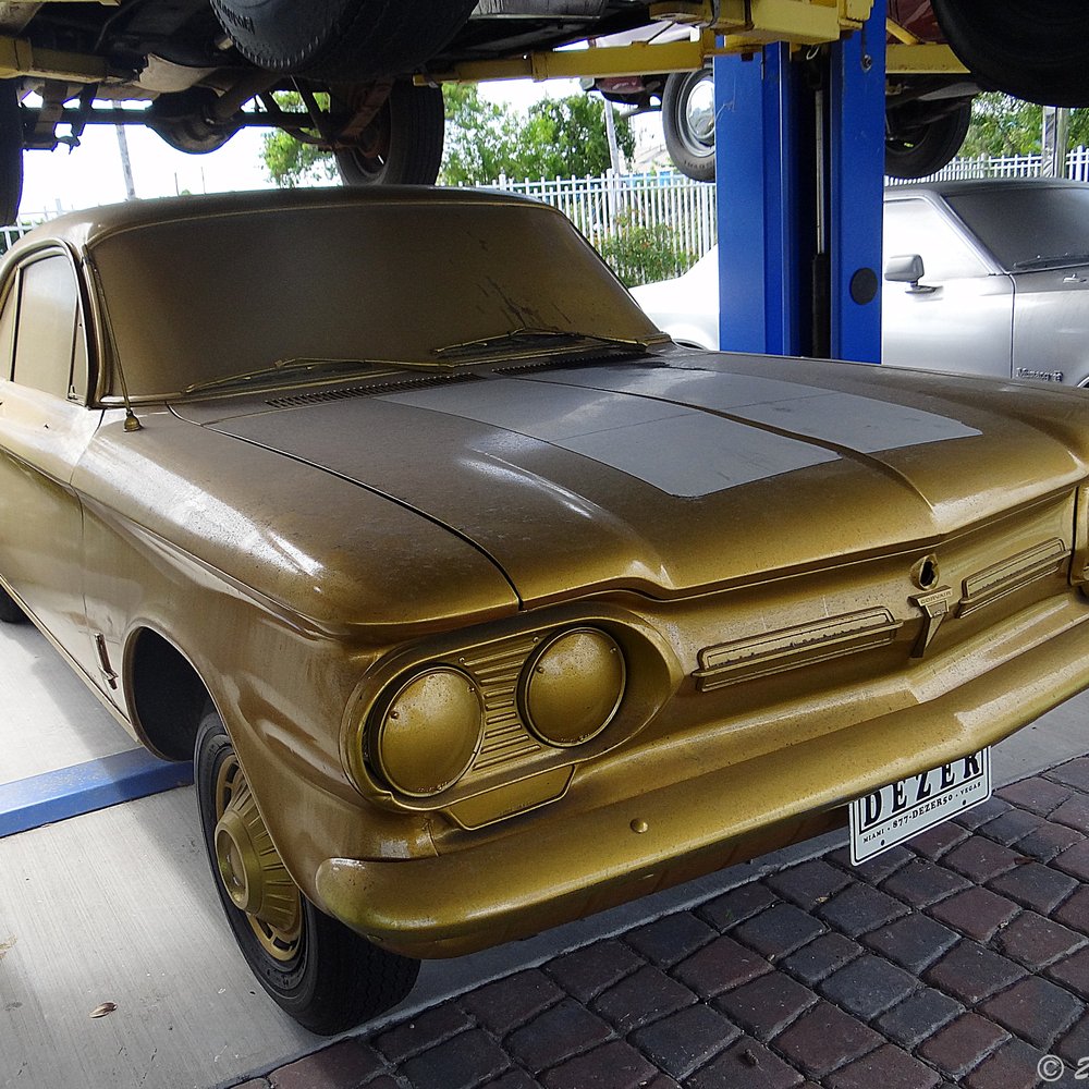Orlando Auto Museum - A Chevrolet Corvair, in gold paint.  The only American-designed, mass-produced passenger car to feature a rear-mounted air-cooled engine. - Museums Near Me - Orlando, Florida