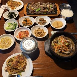 Bulgogi hot plate (top middle) and hot pot (bottom right) with banchan in bowls and seafood pancakes on plates Bulgogi hot plate (top middle) and hot pot (bottom right) with banchan in bowls and seafood pancakes on plates
