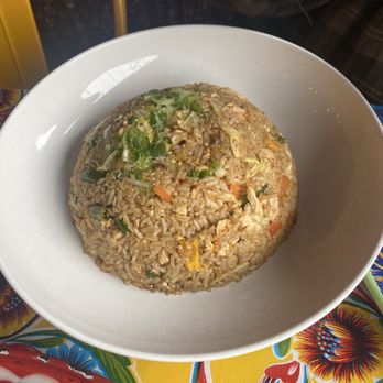 Kai Yang - Chicken Basil Fried Rice - A white bowl contains fried rice with vegetables and chopped green onions, placed on a colorful tablecloth. - Thai Near Me - Montclair, New Jersey