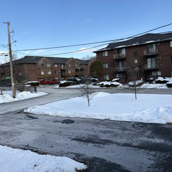Safe Responsible Movers - Residential apartment buildings made of brick are visible, with snow covering the lawns and some patches of ice on the roads. Small trees without leaves are planted along the area, and power lines run across the sky. The scene depicts a cold winter day in a suburban neighborhood. - Movers Near Me - Boston, Massachusetts