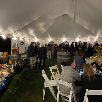 Paumanok - a group of people sitting at tables under a tent - Wineries Near Me - Aquebogue, New York