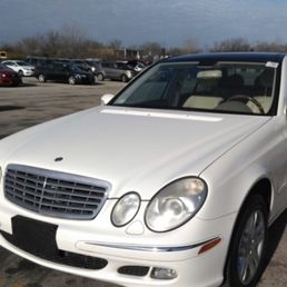 One of the cars they fixed - A white Mercedes-Benz E-Class sedan parked in a busy parking lot with multiple cars and people in the background.