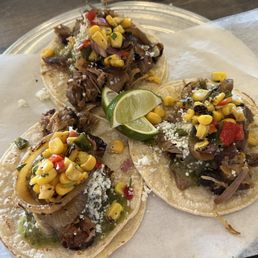 Carnitas street tacos with tomatillo salsa, corn salsa, grilled onions, queso fresco.
