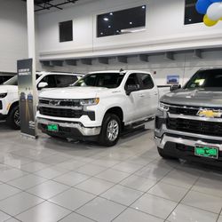Quirk Chevrolet - Quirk Chevrolet dealership interior with current showroom vehicles, featuring the Chevrolet Silverado 1500 lineup.