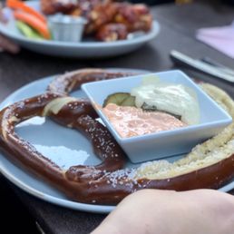 a large pretzel with a bowl of dip