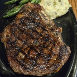 Bone in rib eye steak with mash potatoes and green beans.