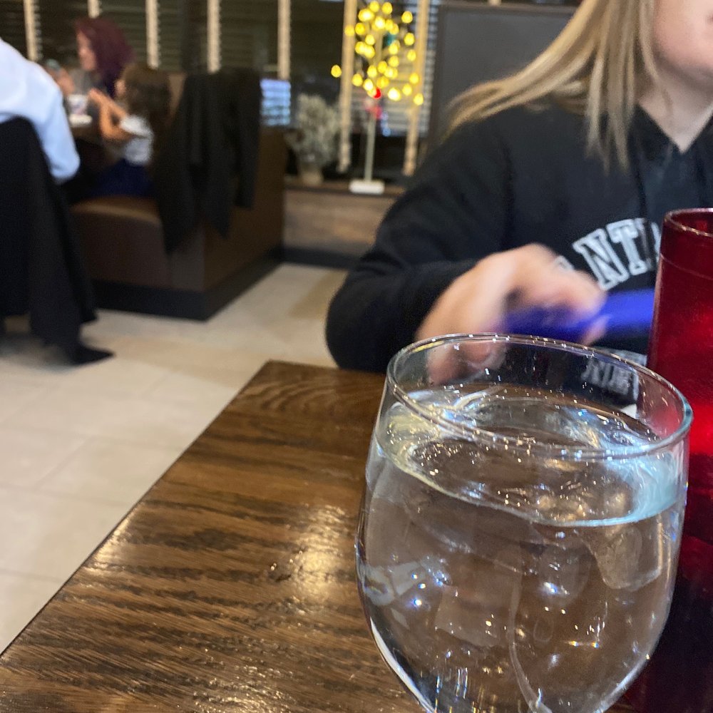 a woman sitting at a table with a glass of water a woman sitting at a table with a glass of water