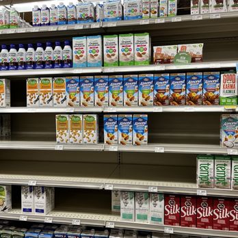 Natural Grocers - Nondairy milks - Store shelves at Natural Grocers in Albuquerque, NM, are stocked with a variety of nondairy milk products such as almond, soy, and coconut milk. The products are organized in rows, with different brands and flavors visible, including organic and flavored options. The shelves are well-stocked, with price tags visible beneath each product. The store environment appears clean and orderly, focusing on plant-based milk alternatives. - Grocery Near Me - Albuquerque, New Mexico