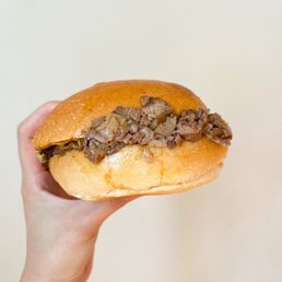 a hand holding a beef sandwich