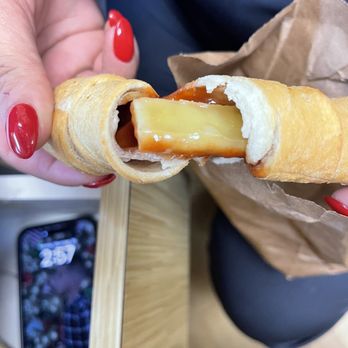 Vicky Bakery - a person holding a hot dog wrapped in a pastry - Bakeries Near Me - Boca Raton, Florida