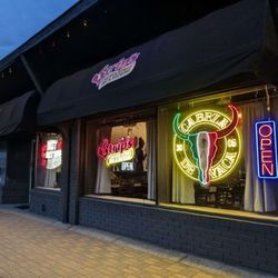 Front windows lit up with neon signs at night.