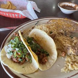 Tacos al pastor, rice and beans. Chips and salsa in the background.