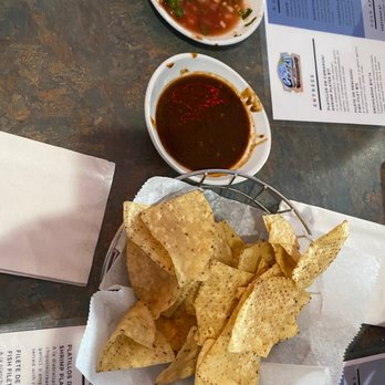 La Costa Bora - A basket of tortilla chips with two small bowls of salsa and sauce on a restaurant table, with menus and napkin nearby. - Seafood Near Me - Belvidere, Illinois